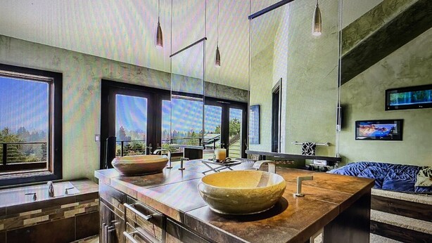 Una cucina moderna con una grande isola, elettrodomestici integrati e ampie finestre che offrono vista sull'esterno.