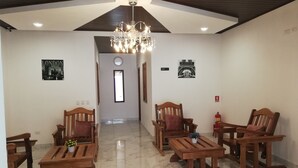 Amplia sala de estar con techo alto, muebles de madera, un candelabro y vista al comedor.