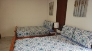 Una cama doble con ropa de cama estampada, una mesita de noche con lámpara y una ventana con persianas.