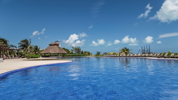 Una piscina al aire libre, sombrillas, sillones reclinables de piscina