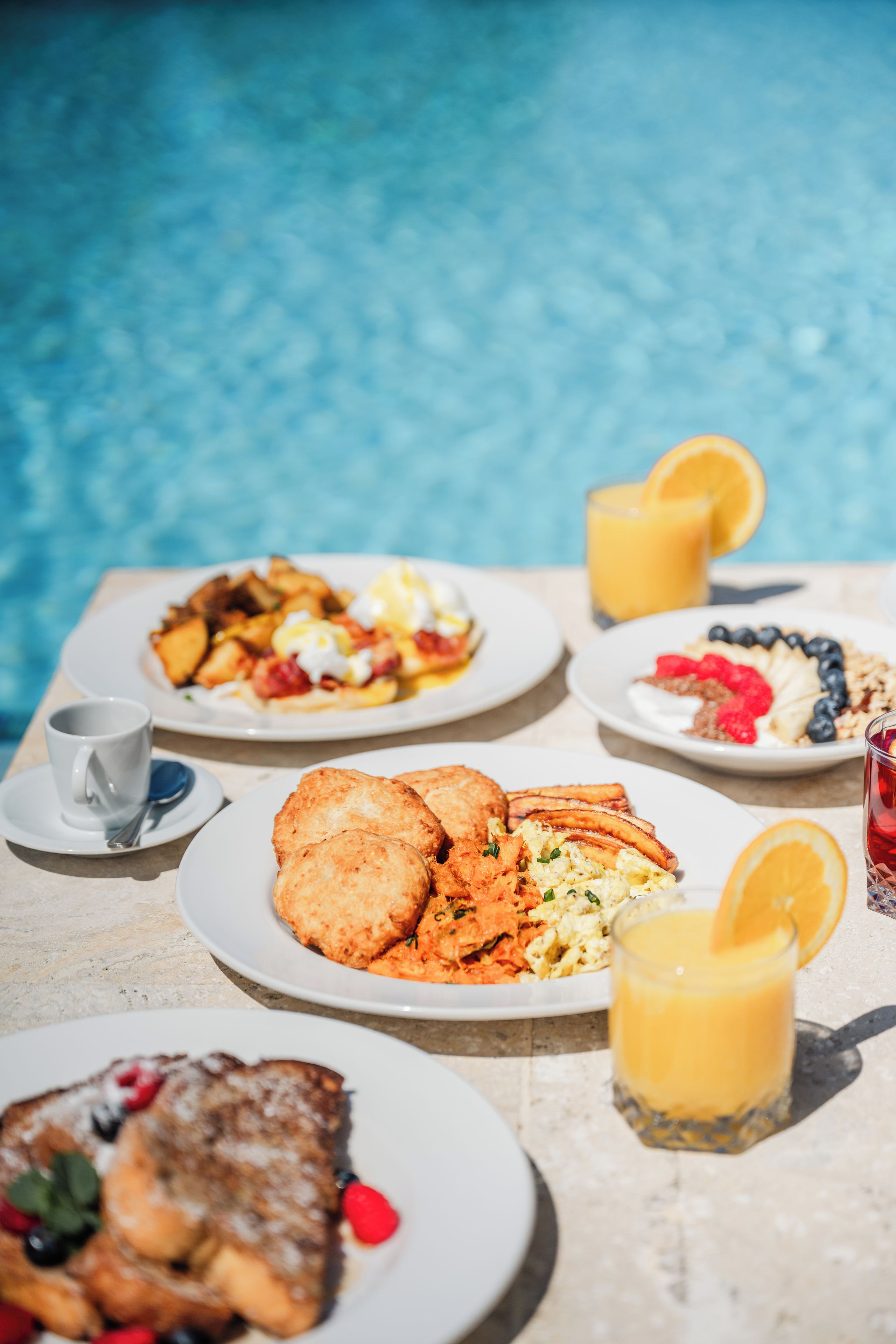 A dining table with breakfast plates, a glass of orange juice, and a cup.