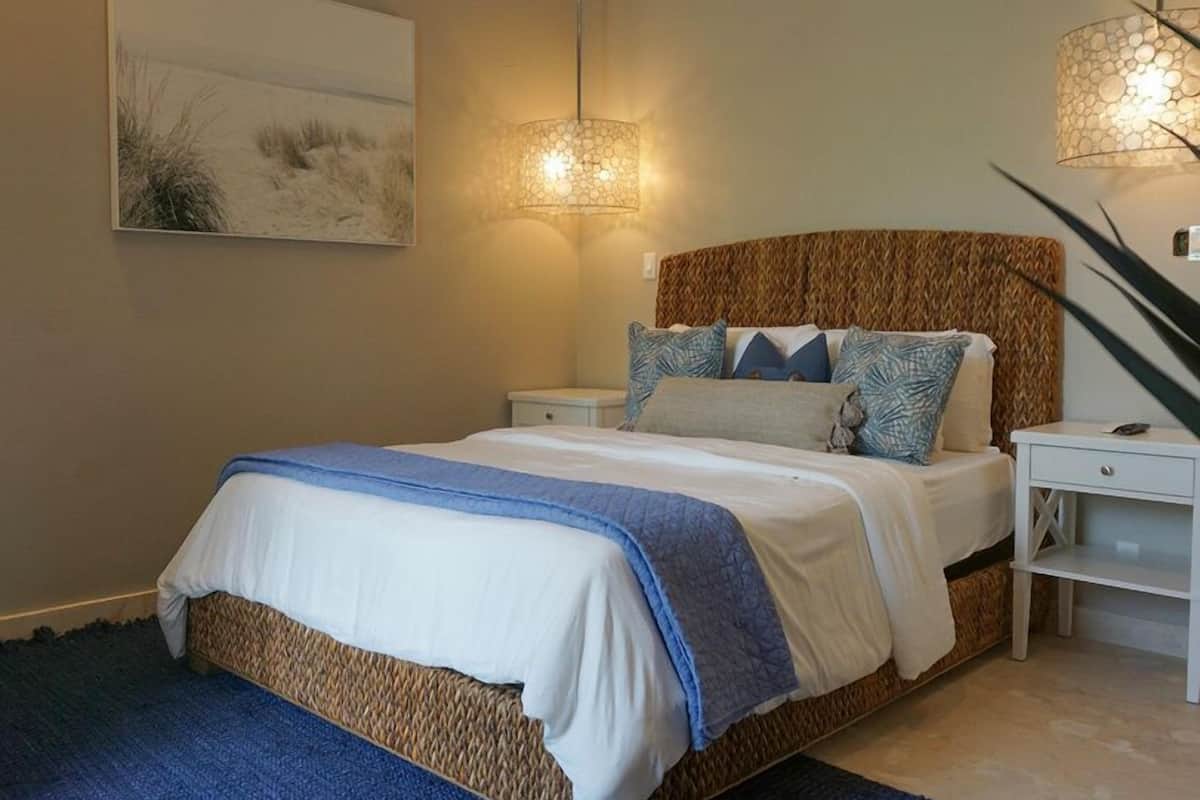 A bedroom with a bed, bedside tables, a ceiling fan, and a wall-mounted lamp.