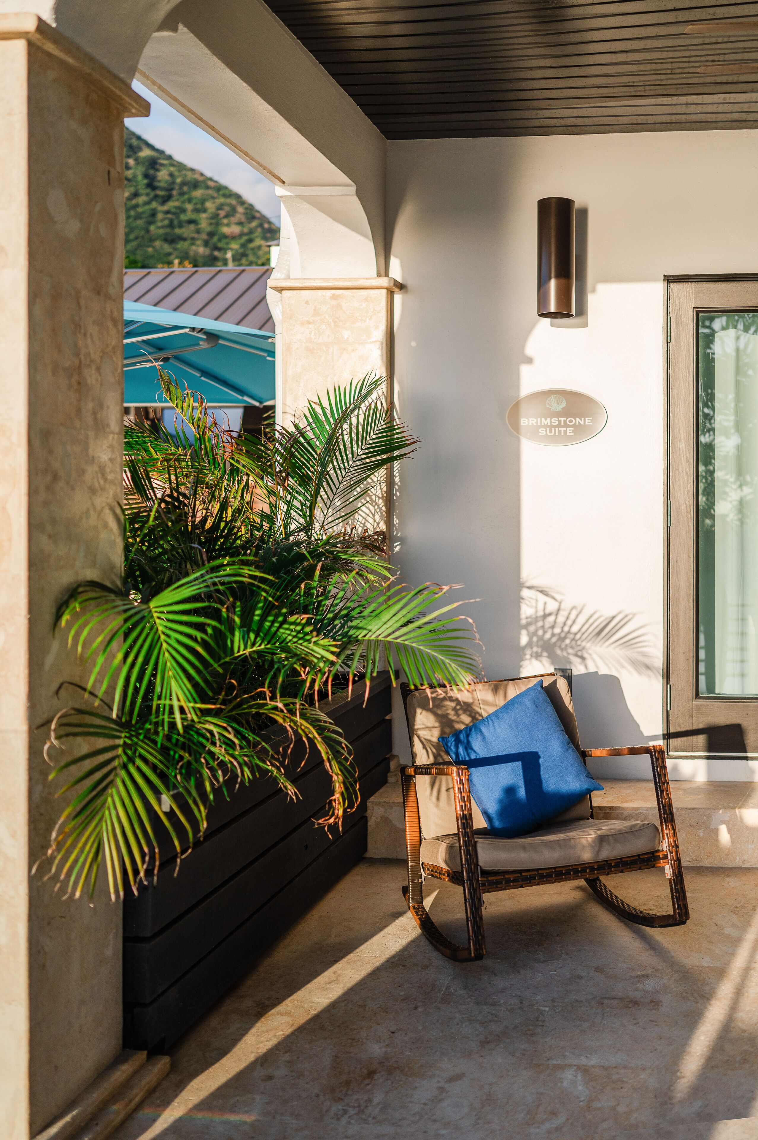 A room with a rocking chair, a potted plant, and a sign indicating a suite.