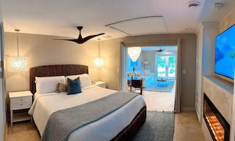 Un dormitorio moderno con una cama grande, un ventilador de techo, un televisor y vistas a un balcón.