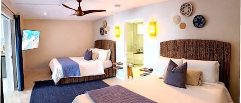 A hotel room with two beds, a ceiling fan, wall sconces, and a television.