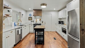 Une cuisine moderne avec des meubles blancs, un réfrigérateur en acier inoxydable et une table en bois.