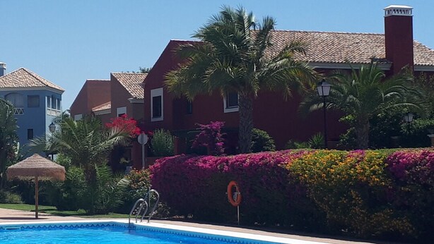 A swimming pool with a clear blue water surface, surrounded by a brick walkway.