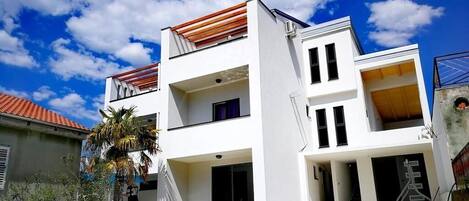 A modern two-story building with a swimming pool in front.
