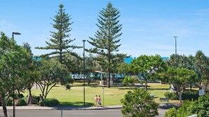 A park with walking paths, large trees, and a clear sky.