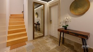 Eine Holztreppe führt zu einem Raum mit einem großen Spiegel, einer runden Wanddekoration und einem Holzkonsolentisch mit einem Blumentopf.
