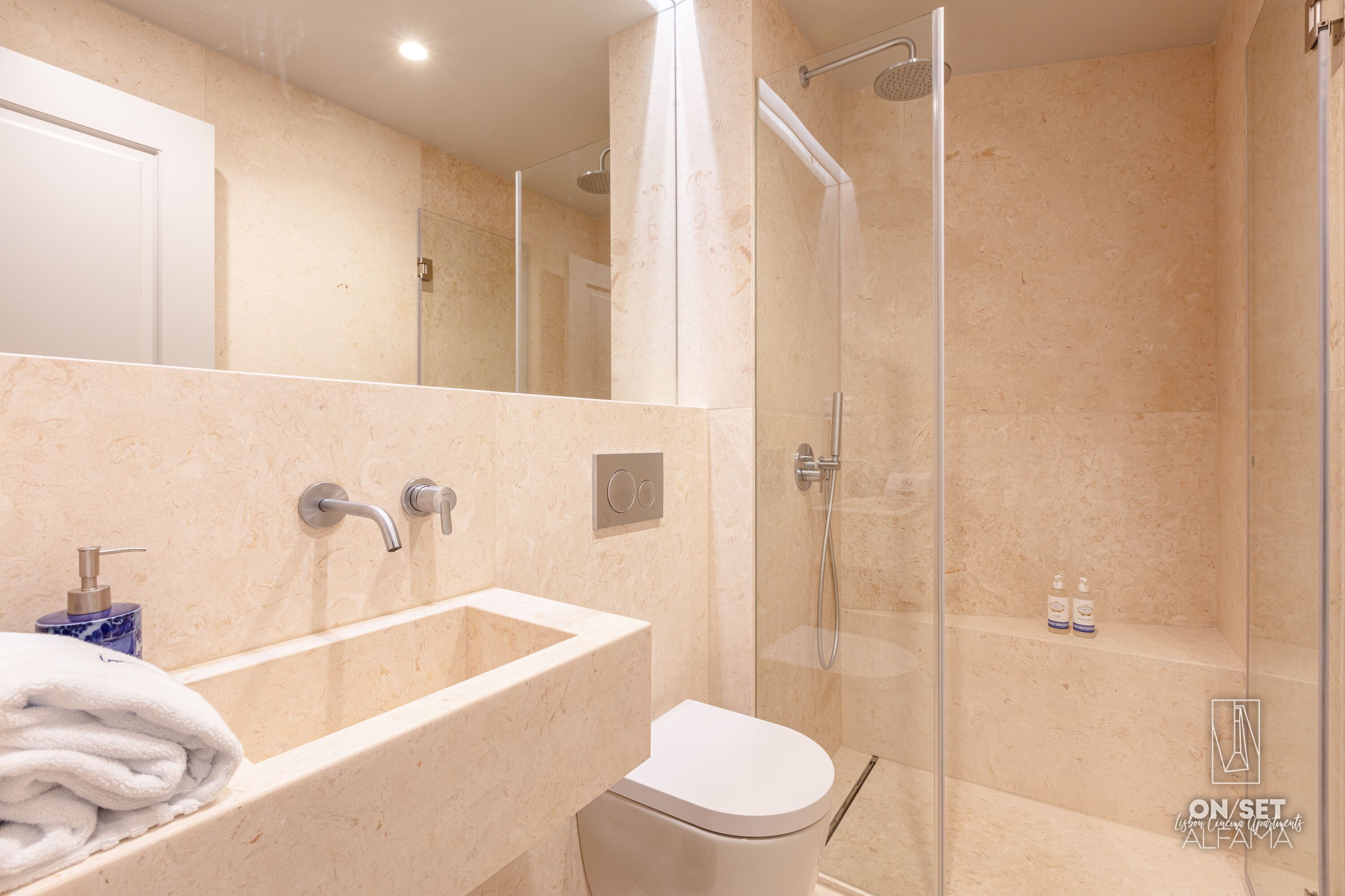 A modern bathroom with a marble sink, a toilet, and a glass-enclosed shower.