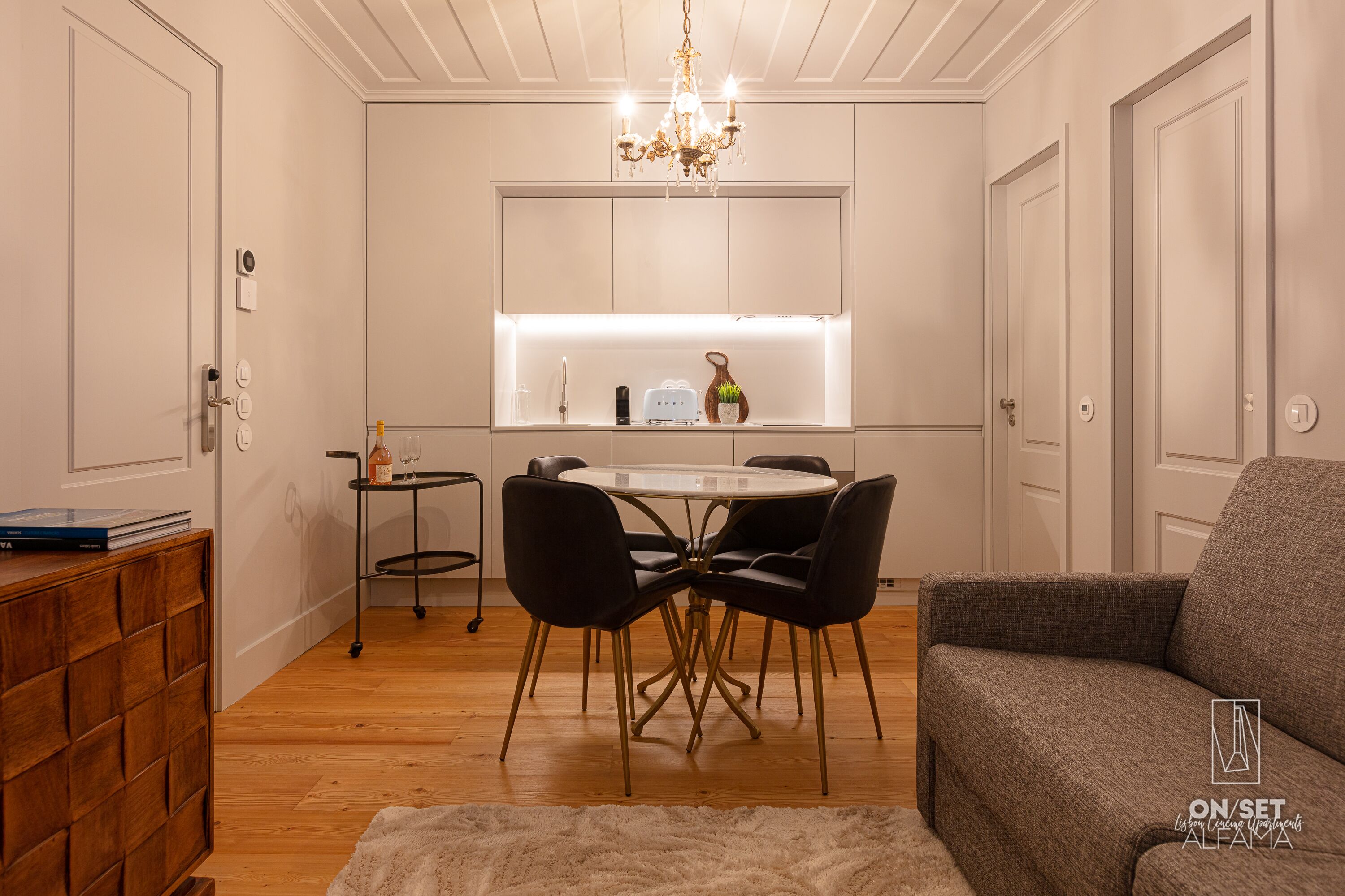 A compact living space with a dining area, a sofa, and a chandelier.