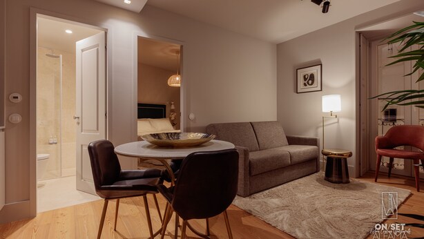 Un salon moderne avec une table ronde, deux chaises, un canapé, un lampadaire et un fauteuil rouge.