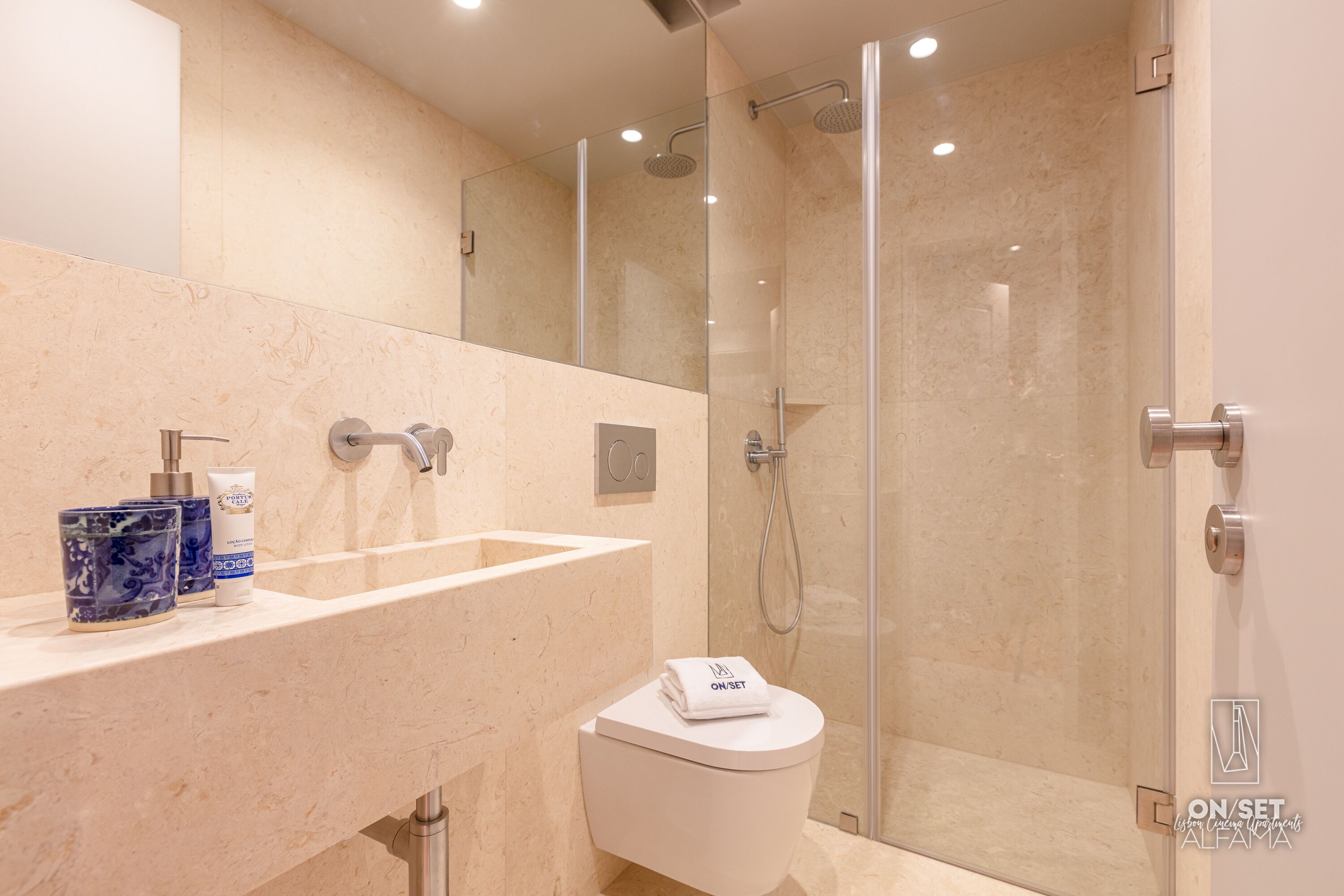 A modern bathroom with a marble sink, a toilet, and a glass-enclosed shower.