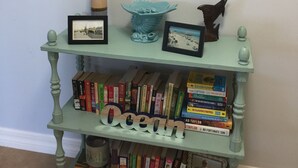 A bookshelf with various books and decorative items. - Ocean Front, Luxurious 3/3 New Rental (Daytona Beach Shores)