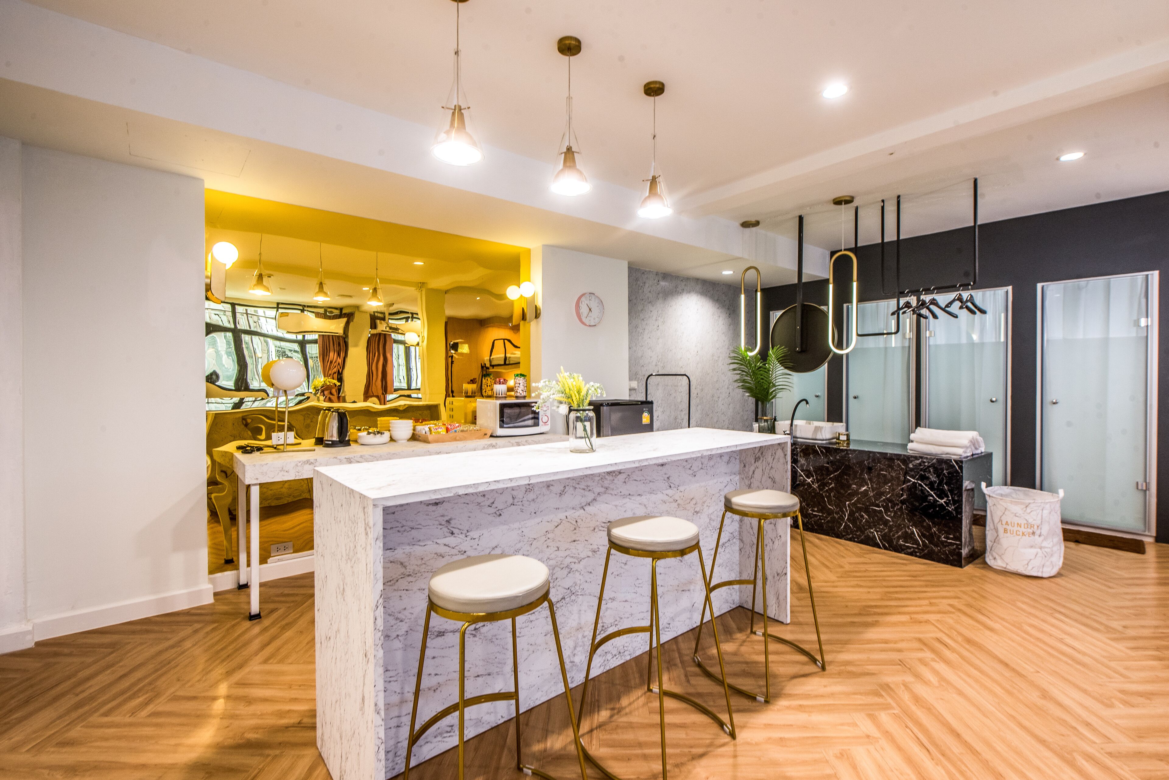 A modern kitchen with a marble island, bar stools, pendant lighting, and a view into the dining area.