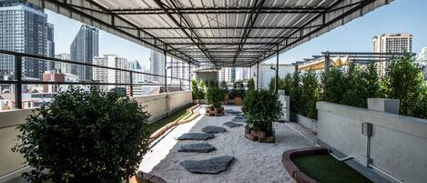 A rooftop terrace with a metal roof, potted plants, and a gravel path.