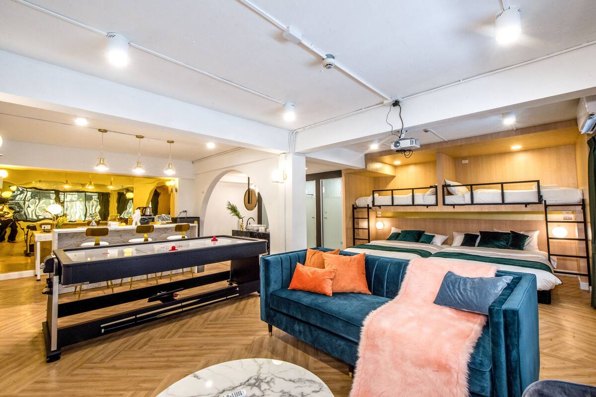 Habitació d'hotel moderna amb taula de bitlles, sofà, llits superposats i zona de menjador.