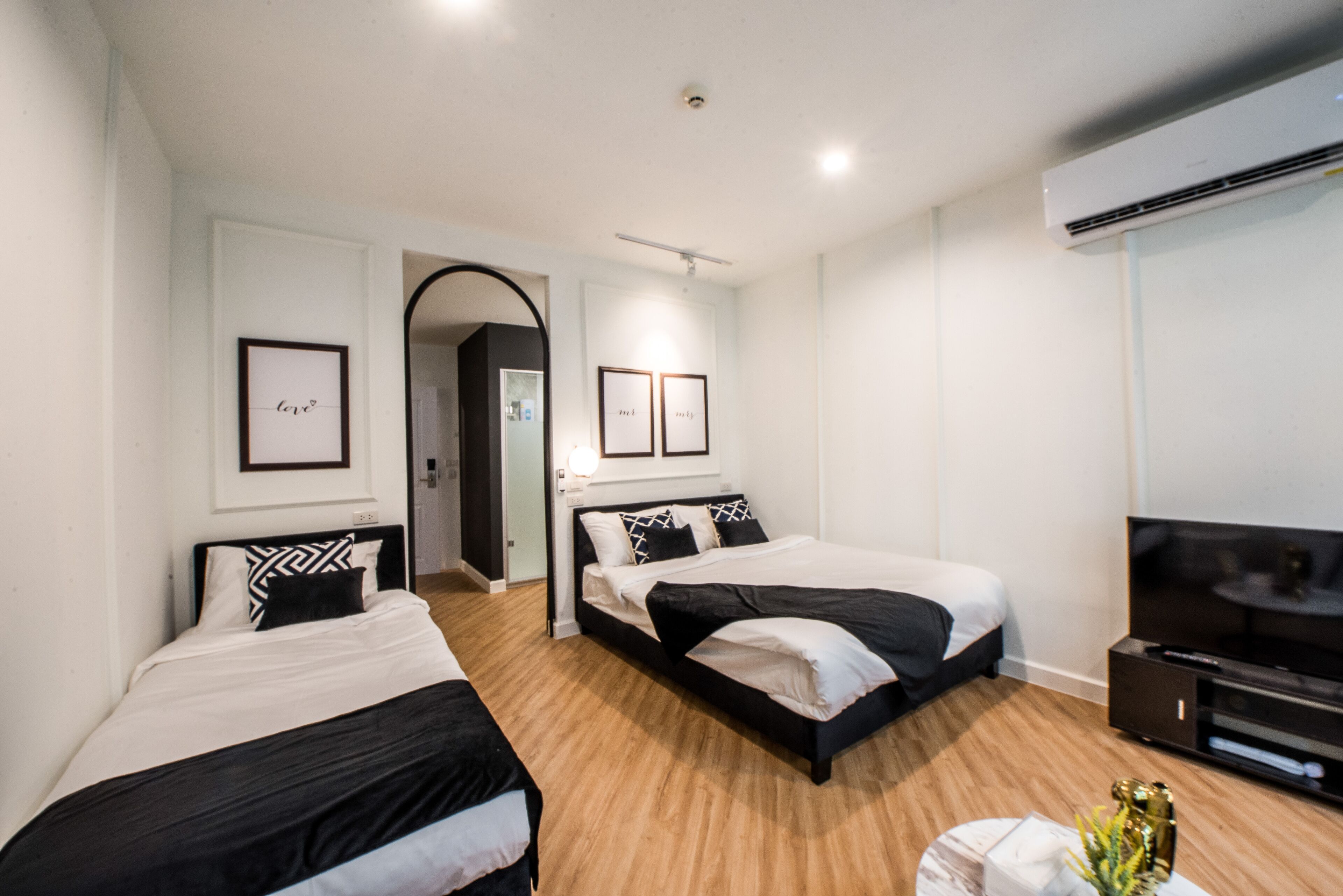 A modern hotel room with two beds, a TV, and a small plant.