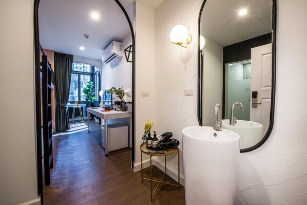 Un baño moderno con dos lavamanos, un espejo grande y una pequeña mesa con artículos de aseo.