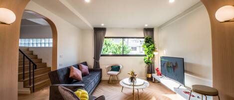 A modern living room with a sofa, armchairs, a coffee table, and a TV.