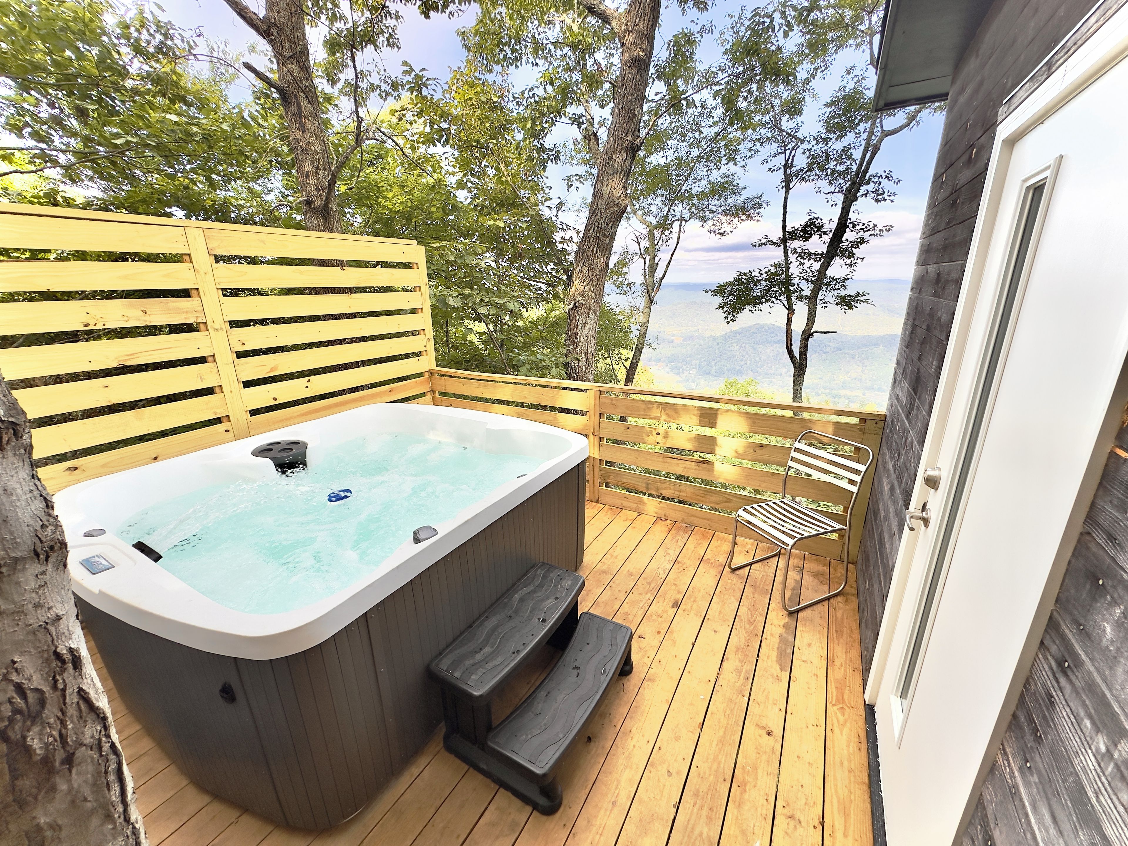 Un bain à remous sur une terrasse en bois, avec vue sur le paysage.