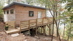Una baita di legno con veranda, immersa tra gli alberi.