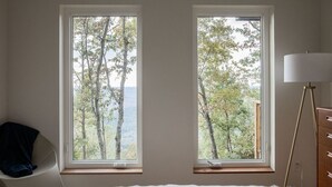Una camera da letto con due finestre che si affacciano su una zona boschiva.