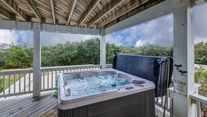 A wooden deck with a hot tub, a covered area, and a view of trees and sky. - 1414 - Hope Sanctuary - Whalehead Corolla Escape | Pool, HotTub & Foosball (Corolla)