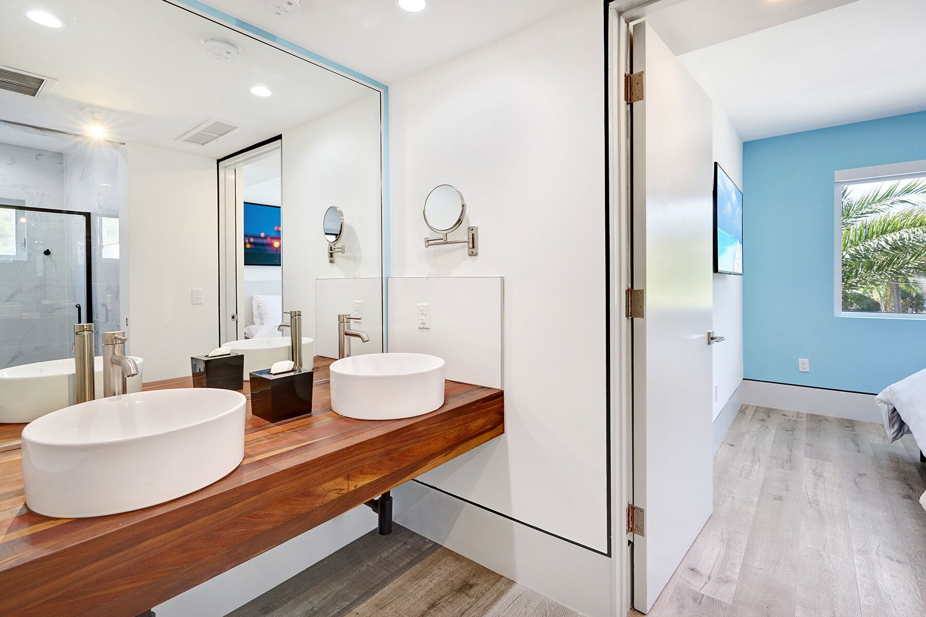A modern bathroom with two sinks, a large mirror, and a shower area.