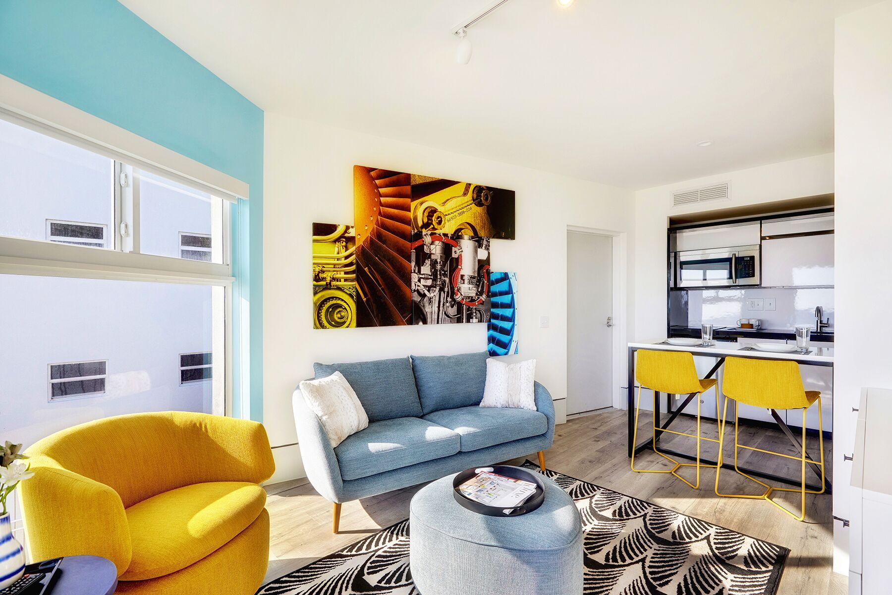 A modern living room with a sofa, a yellow armchair, and a dining area with yellow chairs.