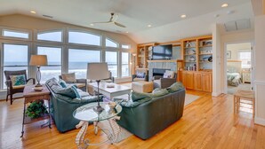 A spacious living room with a large window overlooking the ocean, a fireplace, and a television. - 2869 - Seascape - Oceanfront Duck Retreat w/ Pool, Hot Tub & Views (Kitty Hawk)