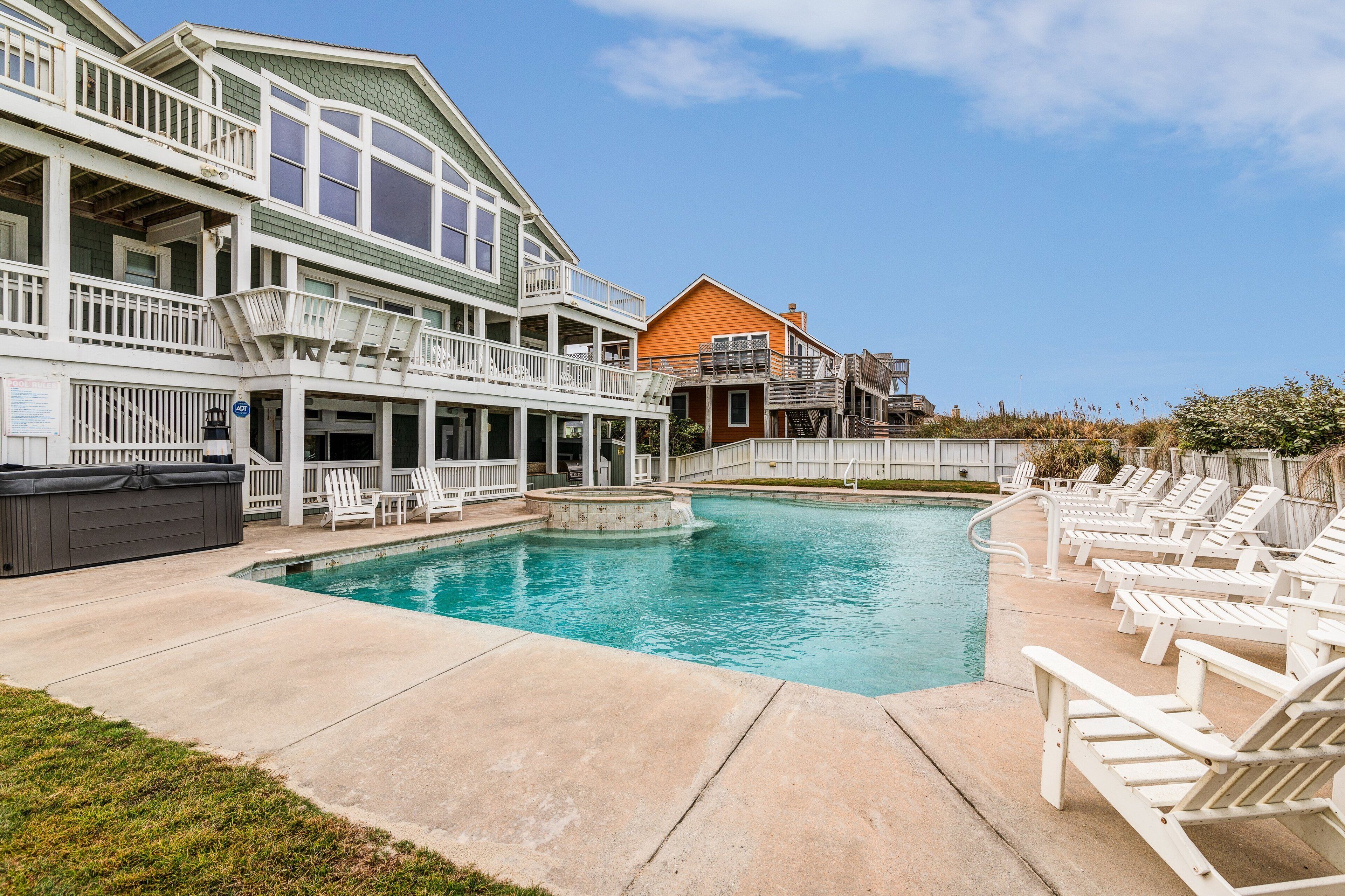 A swimming pool with lounge chairs and a hot tub, surrounded by multi-story buildings with balconies.