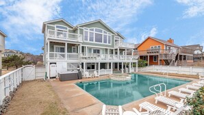 A two-story house with a large swimming pool, outdoor seating, and a covered patio area. - 2869 - Seascape - Oceanfront Duck Retreat w/ Pool, Hot Tub & Views (Kitty Hawk)