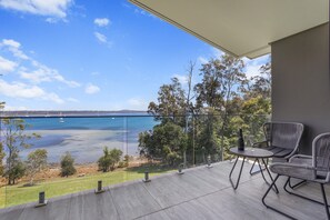 A balcony with a view of a body of water, a table with chairs, and a bottle of champagne. - Maggie's Place Beachfront Retreat in Corlette (Corlette)