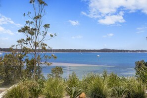 A coastal landscape with clear blue water, boats, and a sandy beach. - Maggie's Place Beachfront Retreat in Corlette (Corlette)