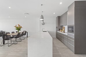 A modern kitchen with a central island, dark cabinetry, and a dining area with a table and chairs.