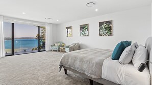 A bedroom with a large bed, a view of the sea, and artwork on the wall. - Maggie's Place Beachfront Retreat in Corlette (Corlette)