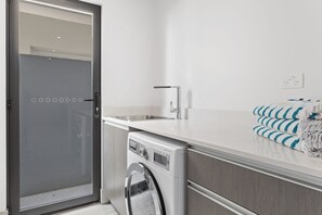 A modern kitchen with a built-in washer and dryer, a countertop, and a towel rack.