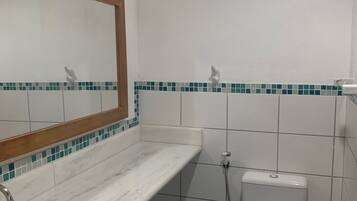 A bathroom with a sink, mirror, toilet, and shower.