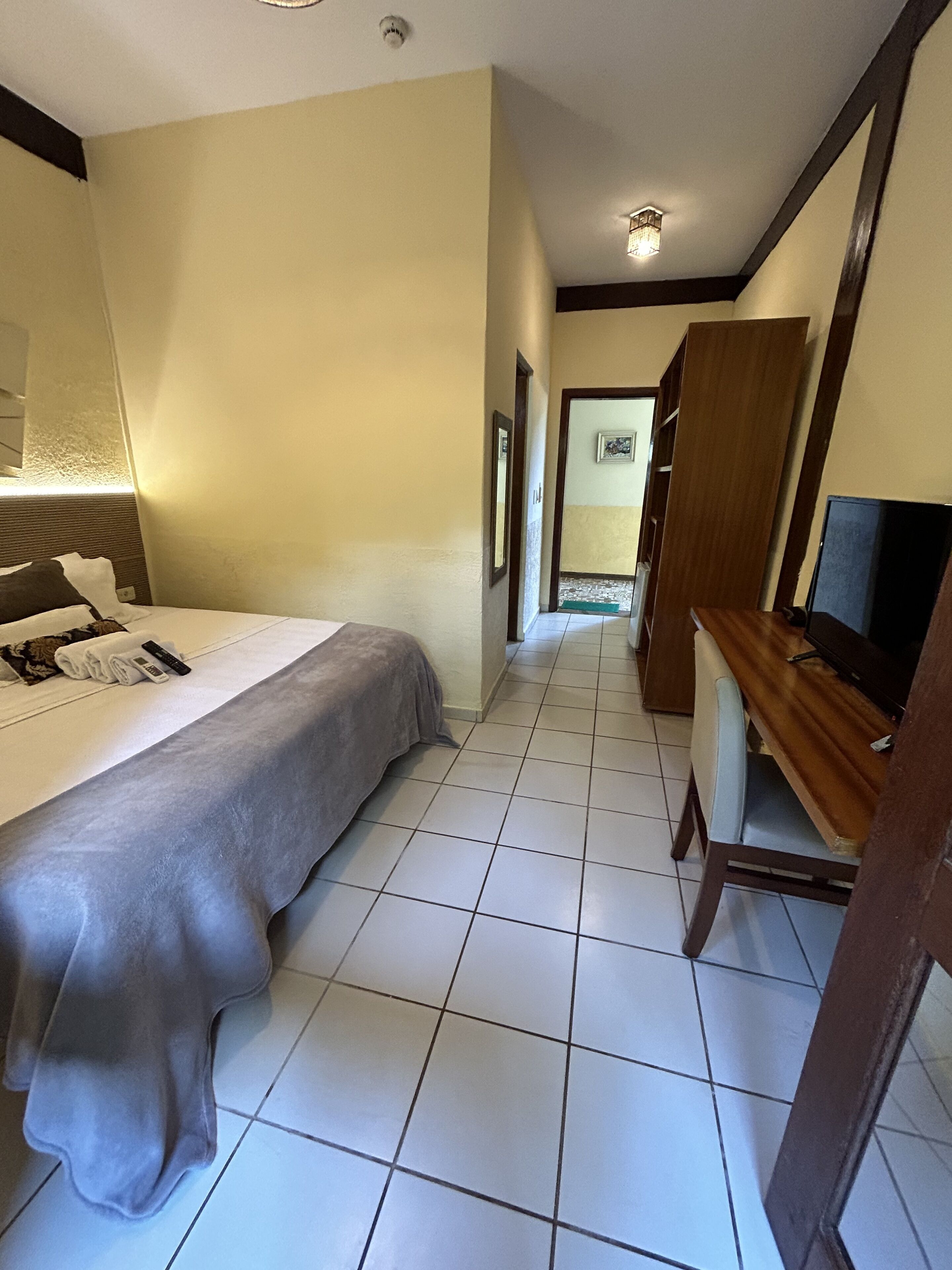 A hotel room with a bed, a wooden desk, and a television.