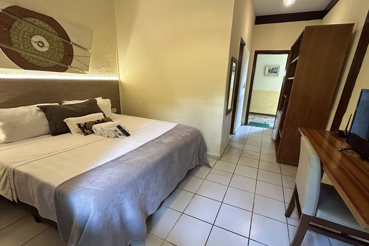 A hotel room with a bed, a desk, and a television.