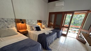 A hotel room with two beds, a wooden headboard, a large sliding glass door leading to a balcony, and a ceiling fan. - Recanto Verde Praia Hotel (São Sebastião)