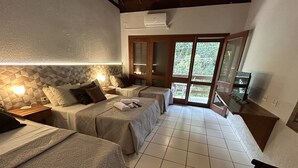 A hotel room with two beds, a TV, and a balcony with a view of greenery. - Recanto Verde Praia Hotel (São Sebastião)