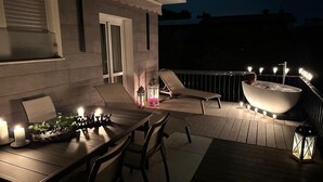 Eine Terrasse im Freien mit Esstisch, Stühlen, einer Liege, einem Whirlpool und Kerzen.
