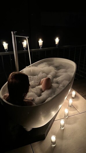 Una persona relajándose en un jacuzzi rodeado de velas.