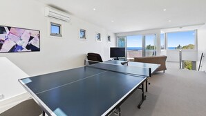 A modern room with a ping pong table, a television, and a view of the sea.