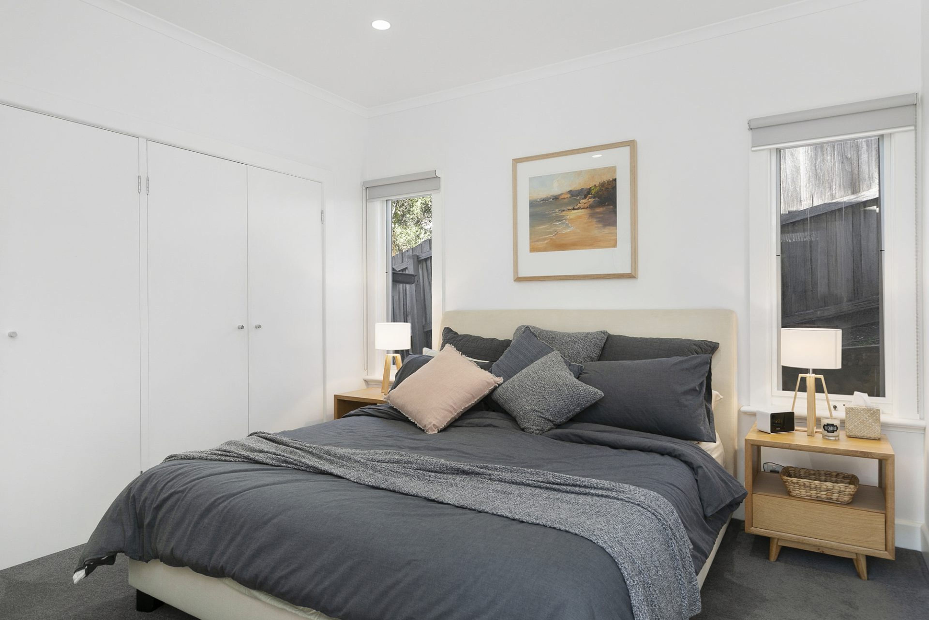 A bedroom with a bed, nightstands, a framed picture, and a wardrobe.