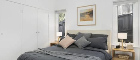 A bedroom with a bed, nightstands, a framed picture, and a wardrobe.