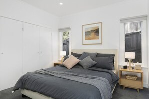 A bedroom with a bed, nightstands, a framed picture, and a wardrobe. - Whitecaps (Lorne)
